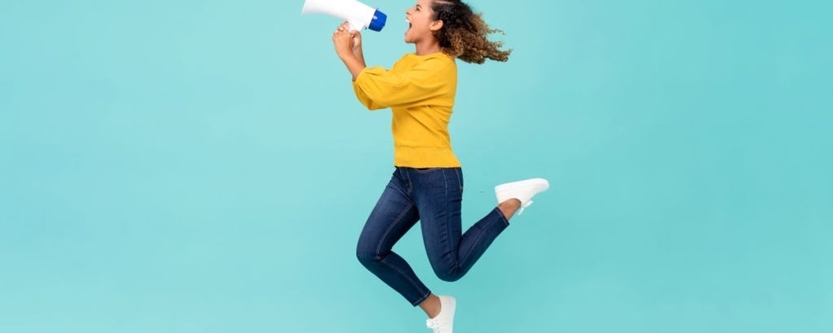 Girl with megaphone jumping and shouting