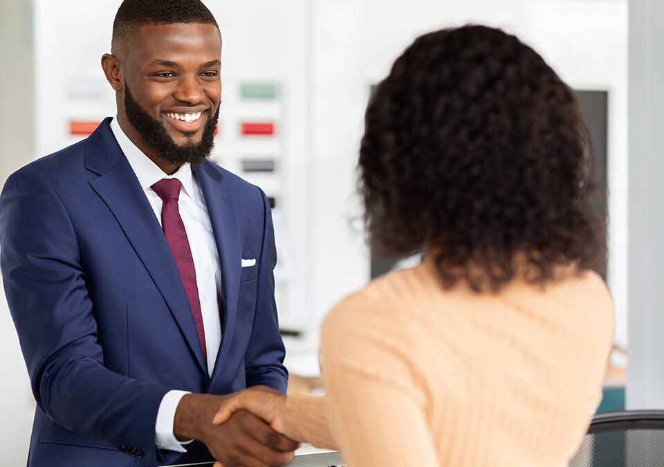 Smiling manager shaking hands with female customer